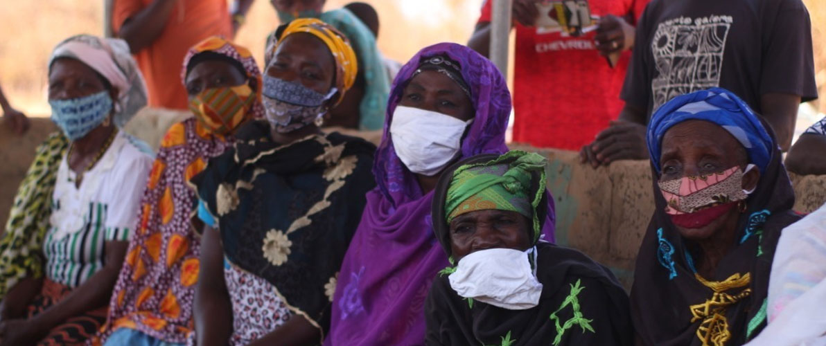 Ghanain women wearing face masks sitting and listening to speakers